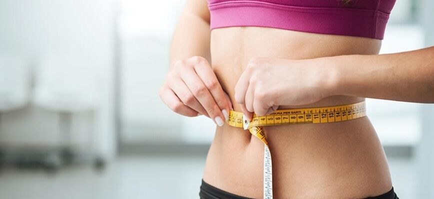 La jeune fille mesure son tour de taille.